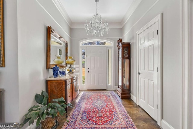 entrance foyer with baseboards, an inviting chandelier, dark wood finished floors, and crown molding