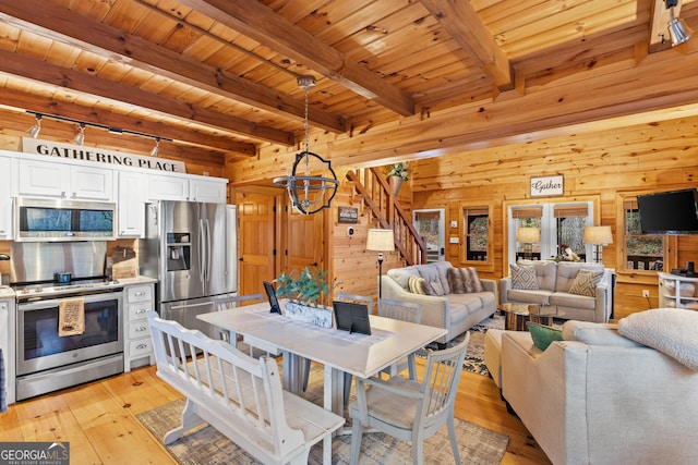 dining area with stairway, wooden walls, wood ceiling, and light wood-style flooring