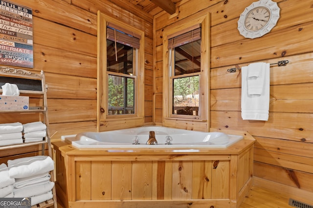 bathroom featuring visible vents, wood walls, and a garden tub