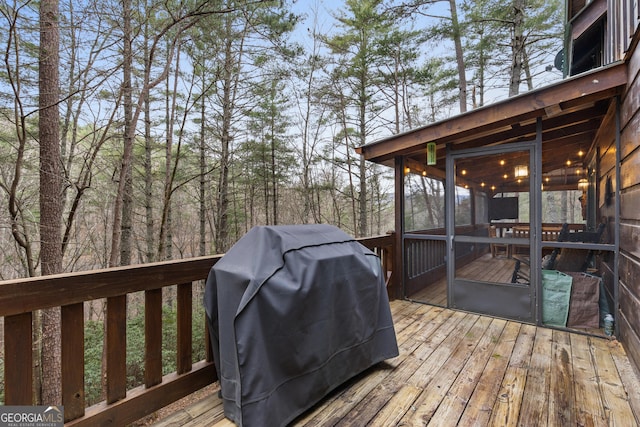 deck with a grill and a sunroom