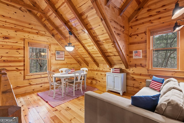 interior space featuring light wood-type flooring, wood ceiling, wood walls, and vaulted ceiling with beams