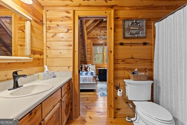 full bath with wood walls, toilet, vanity, and hardwood / wood-style floors