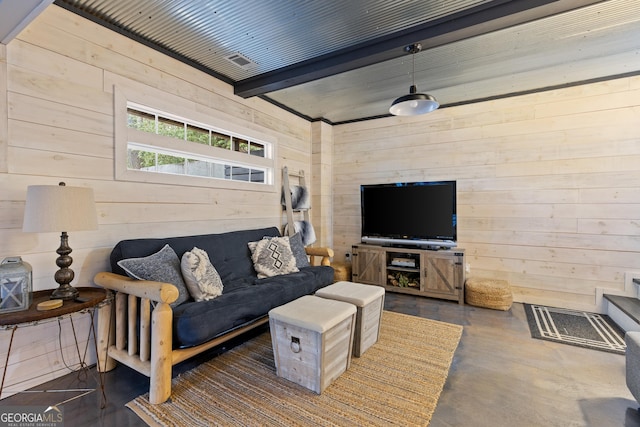 living area featuring beam ceiling, wood walls, and finished concrete floors