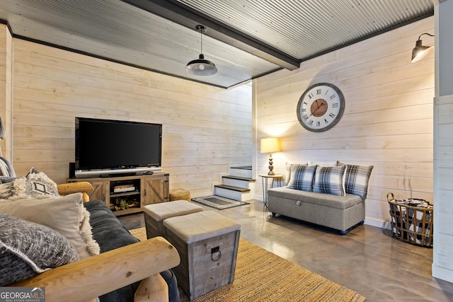 living area with beamed ceiling, concrete floors, wood walls, and stairs