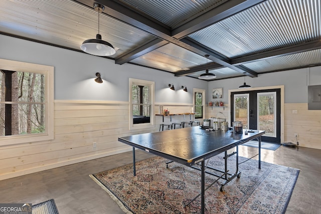 playroom with beam ceiling, finished concrete floors, french doors, wooden walls, and wainscoting