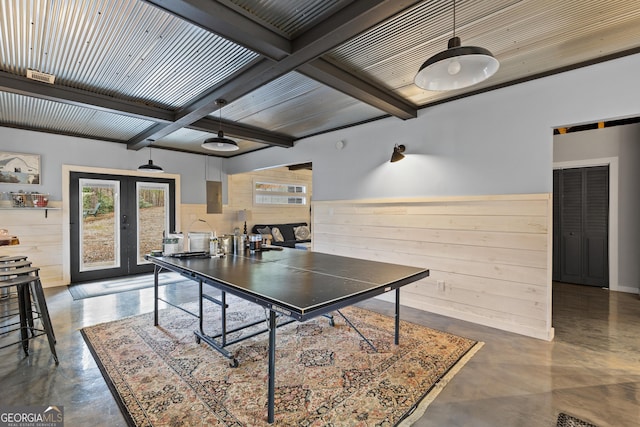 game room featuring beamed ceiling, coffered ceiling, french doors, wood walls, and concrete flooring