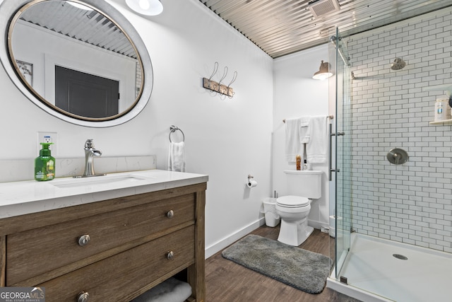 full bath featuring vanity, wood finished floors, baseboards, a shower stall, and toilet