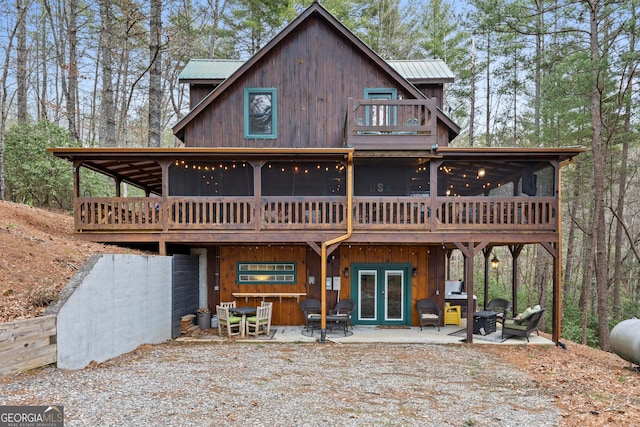 rear view of property featuring french doors, a patio, metal roof, and a sunroom