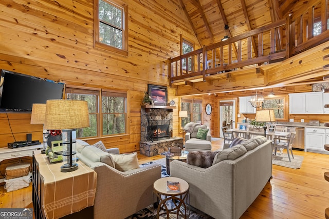 living room with wooden walls, high vaulted ceiling, a fireplace, light wood-style floors, and wood ceiling