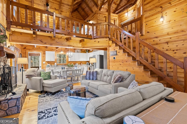 living area featuring stairway, wooden walls, a fireplace, and wooden ceiling