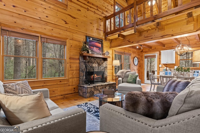 living area featuring an inviting chandelier, a fireplace, light wood-type flooring, and wood walls