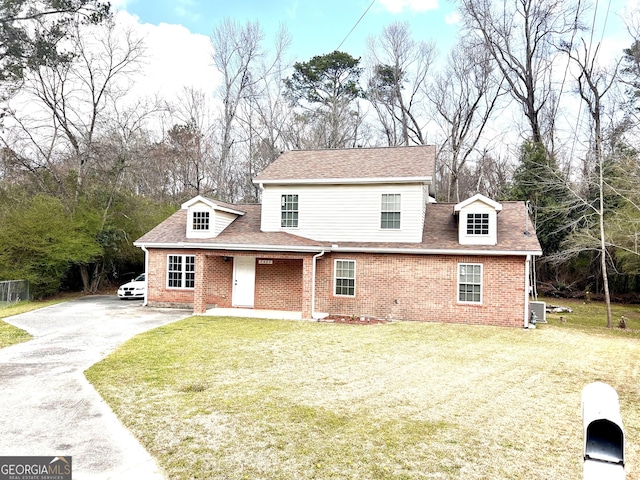 traditional-style house with aphalt driveway, brick siding, a front lawn, and roof with shingles