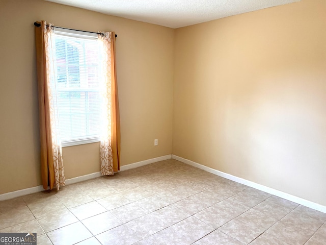 unfurnished room featuring light tile patterned flooring, a textured ceiling, and baseboards