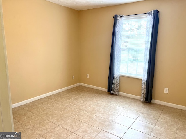 unfurnished room featuring baseboards, a textured ceiling, and a healthy amount of sunlight