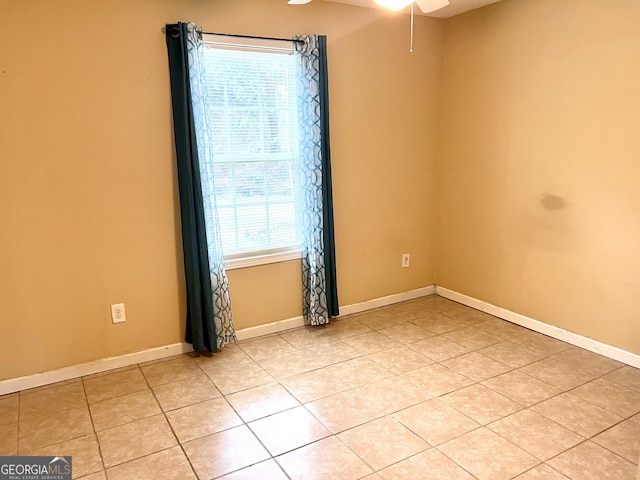 spare room featuring light tile patterned flooring and baseboards