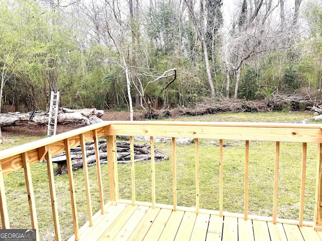 wooden terrace with a view of trees and a lawn