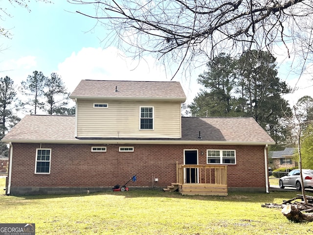 back of house featuring brick siding, a lawn, and roof with shingles