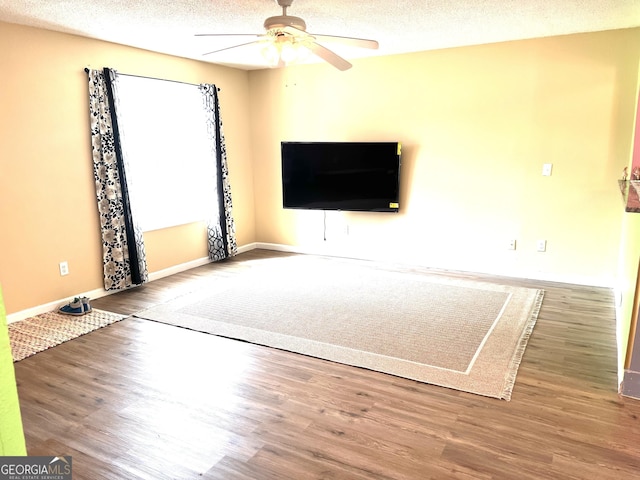 unfurnished living room featuring baseboards, a textured ceiling, ceiling fan, and wood finished floors