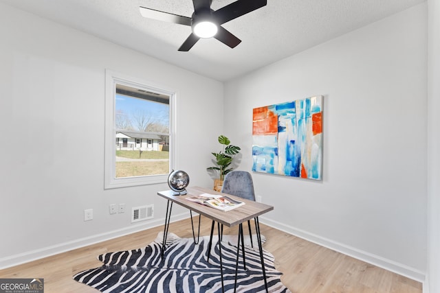 office with visible vents, a ceiling fan, baseboards, and wood finished floors