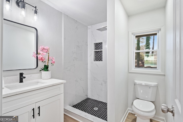 bathroom with a marble finish shower, baseboards, toilet, and vanity