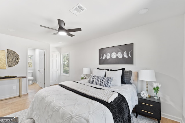 bedroom featuring visible vents, ensuite bath, baseboards, and wood finished floors