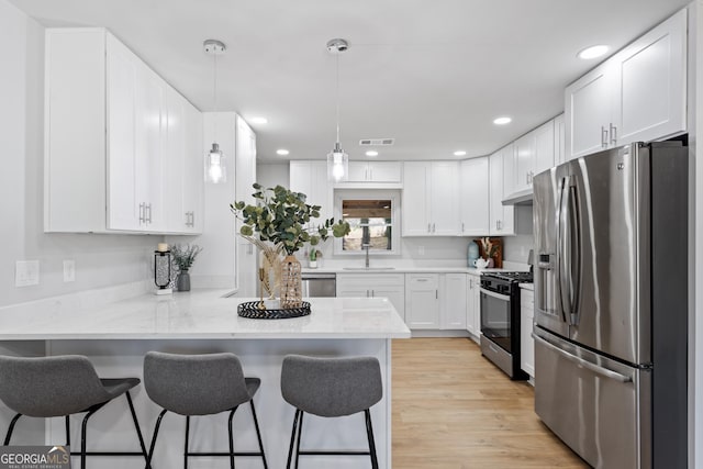 kitchen featuring stainless steel appliances, a peninsula, a breakfast bar area, and visible vents