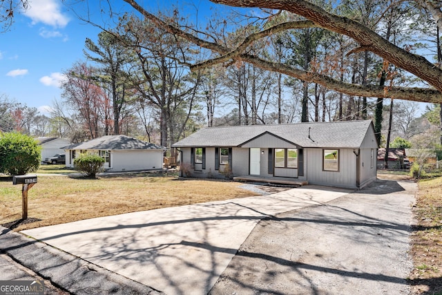 view of front of house with brick siding, driveway, a front yard, and roof with shingles