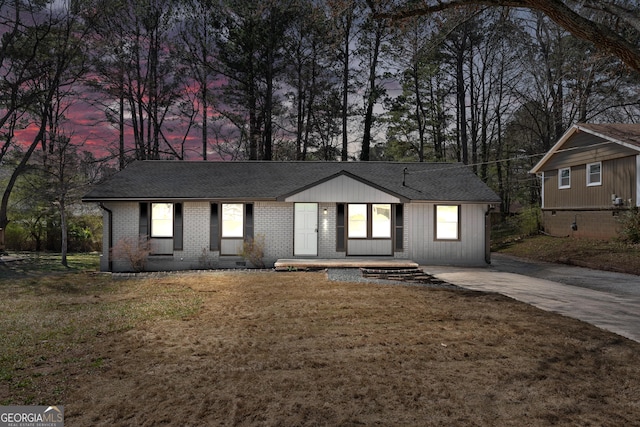 view of front of property featuring a front yard, brick siding, roof with shingles, and crawl space