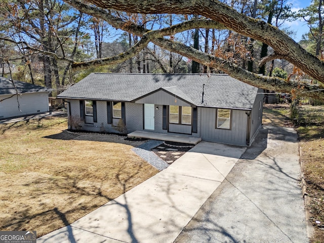 view of front of home with brick siding, concrete driveway, and a shingled roof