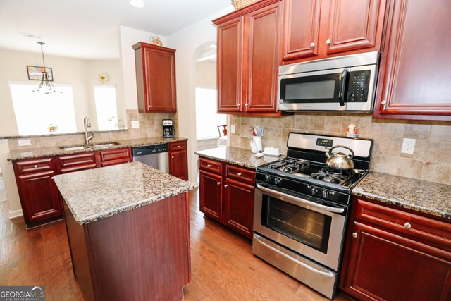 kitchen with a kitchen island, dark wood-style flooring, a sink, dark brown cabinets, and appliances with stainless steel finishes