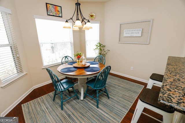 dining space with dark wood-style floors, baseboards, and a chandelier