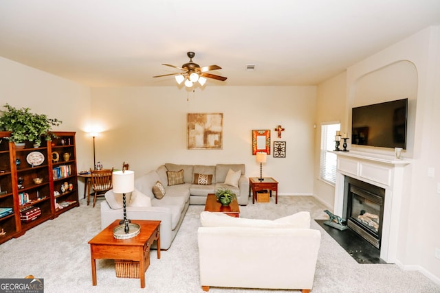 carpeted living room featuring baseboards, a fireplace with flush hearth, a ceiling fan, and visible vents