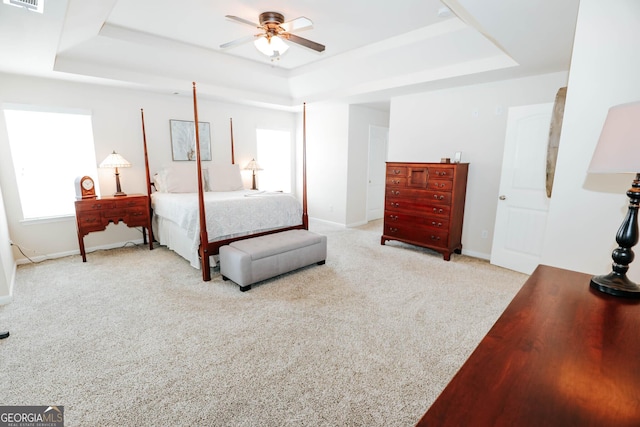 bedroom with a tray ceiling, baseboards, carpet, and visible vents