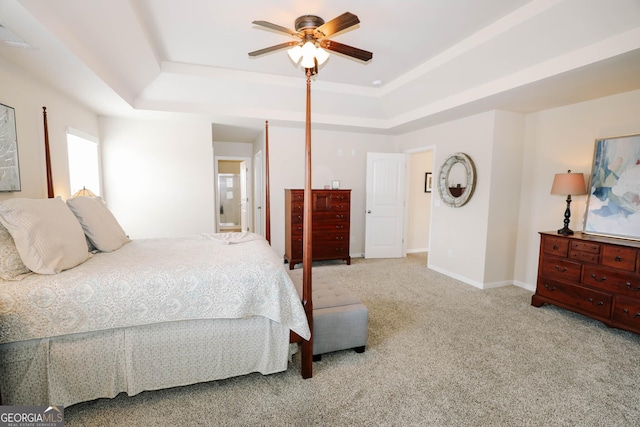 bedroom featuring a tray ceiling, carpet floors, baseboards, and a ceiling fan