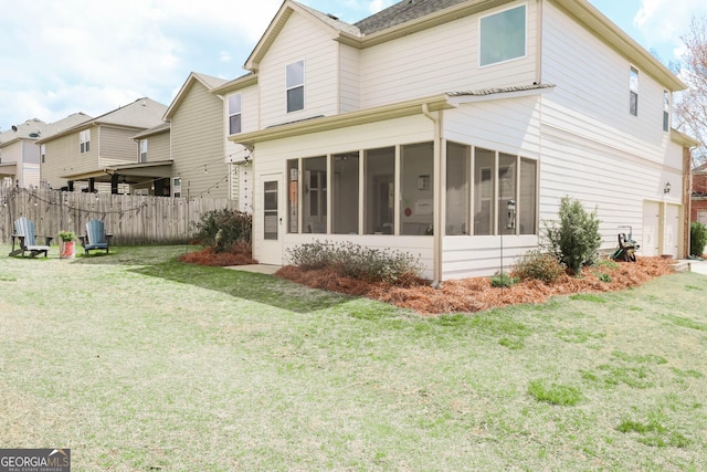 rear view of house featuring a yard, a sunroom, and fence