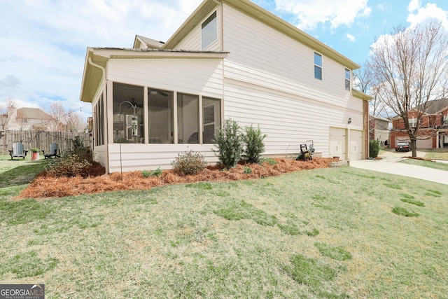 view of home's exterior featuring a lawn, driveway, fence, a sunroom, and a garage