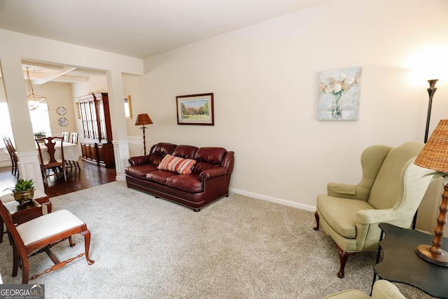 living room featuring an inviting chandelier, carpet, baseboards, and beam ceiling