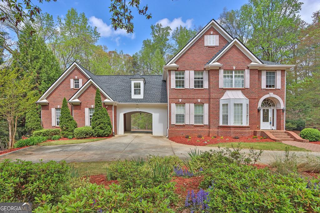 colonial-style house featuring concrete driveway, brick siding, and roof with shingles