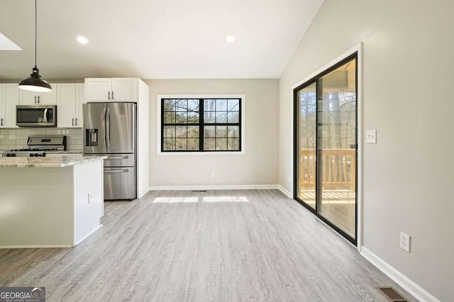 kitchen with stainless steel appliances, plenty of natural light, tasteful backsplash, and white cabinets