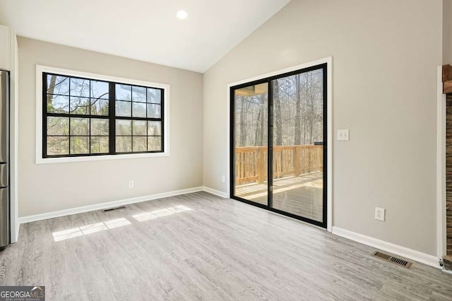 unfurnished room featuring visible vents, wood finished floors, and vaulted ceiling