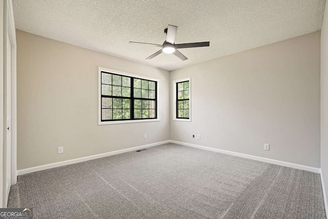 carpeted spare room featuring a ceiling fan, baseboards, and a textured ceiling