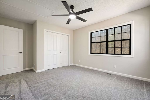 unfurnished bedroom with attic access, carpet, and baseboards