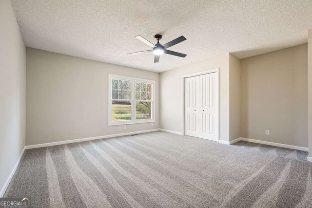 unfurnished bedroom with a closet, baseboards, a textured ceiling, and carpet flooring