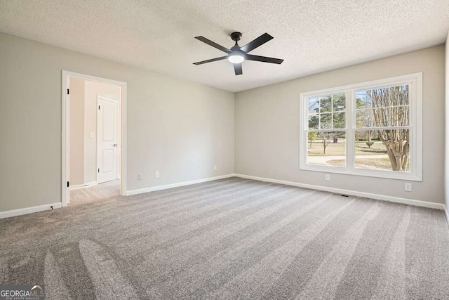 unfurnished room featuring baseboards, carpet, ceiling fan, and a textured ceiling