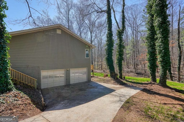 view of property exterior featuring stairway, an attached garage, and concrete driveway