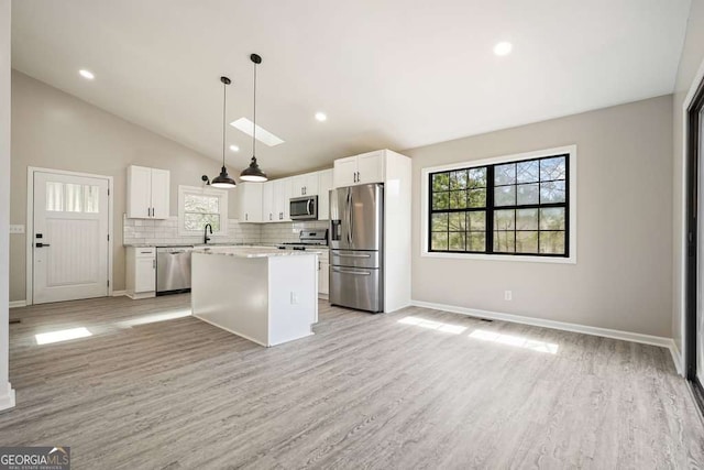 kitchen with white cabinets, a kitchen island, backsplash, and stainless steel appliances