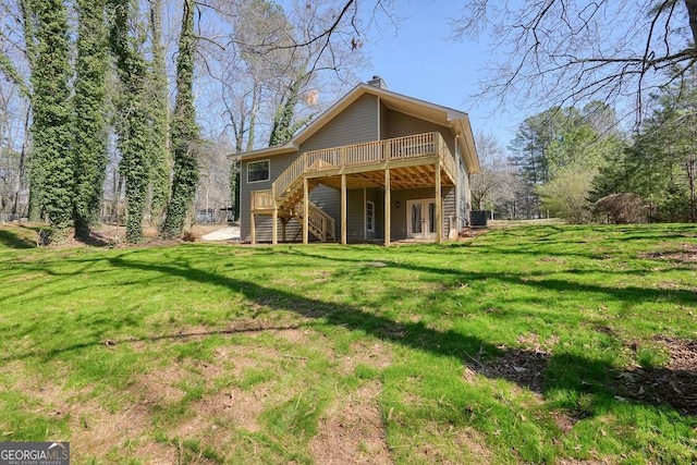 rear view of house with a deck, stairs, and a yard