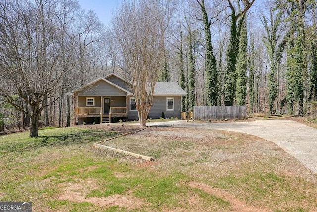 exterior space featuring concrete driveway, fence, and covered porch