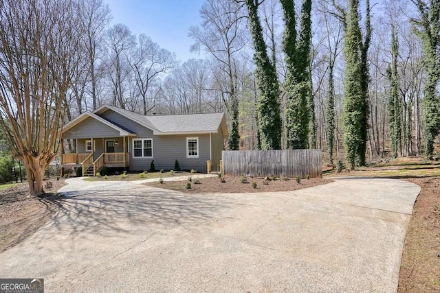 view of front of property with concrete driveway, a porch, and fence