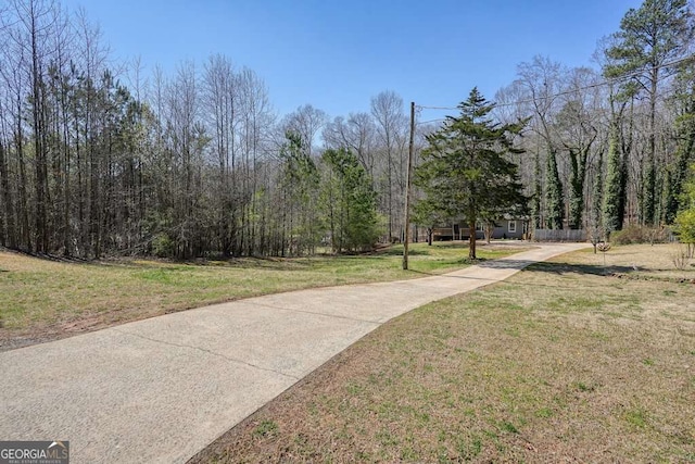 view of property's community featuring a lawn and a forest view